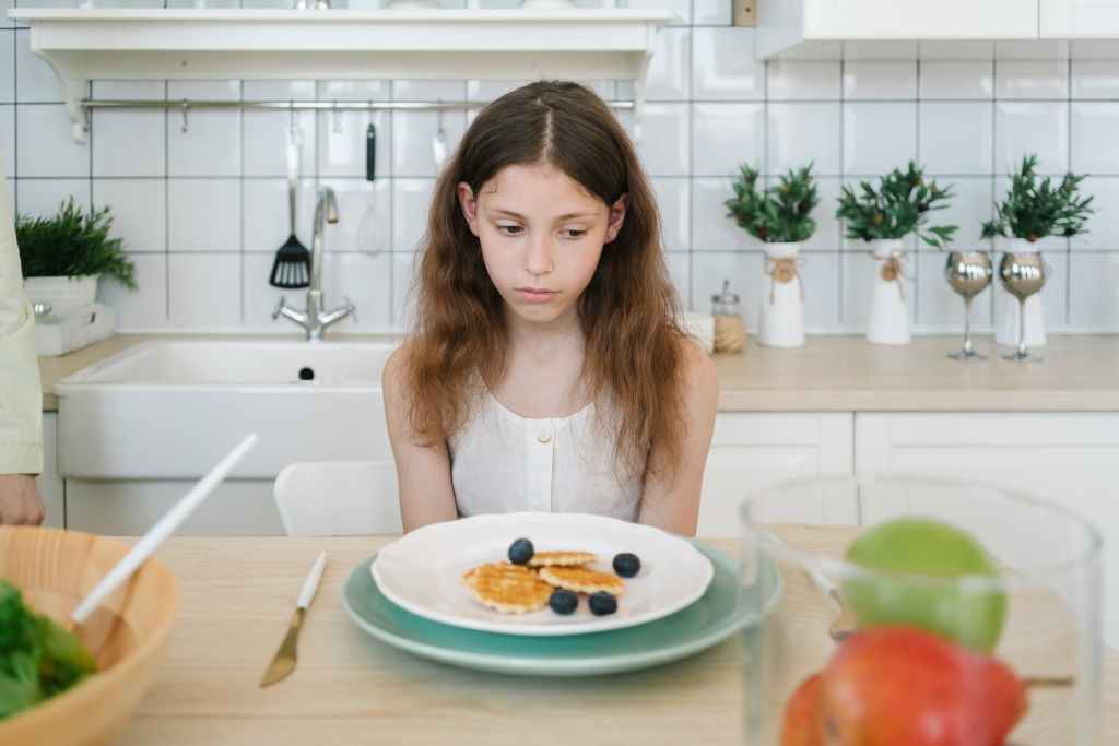 girl sitting in front of a plate with food